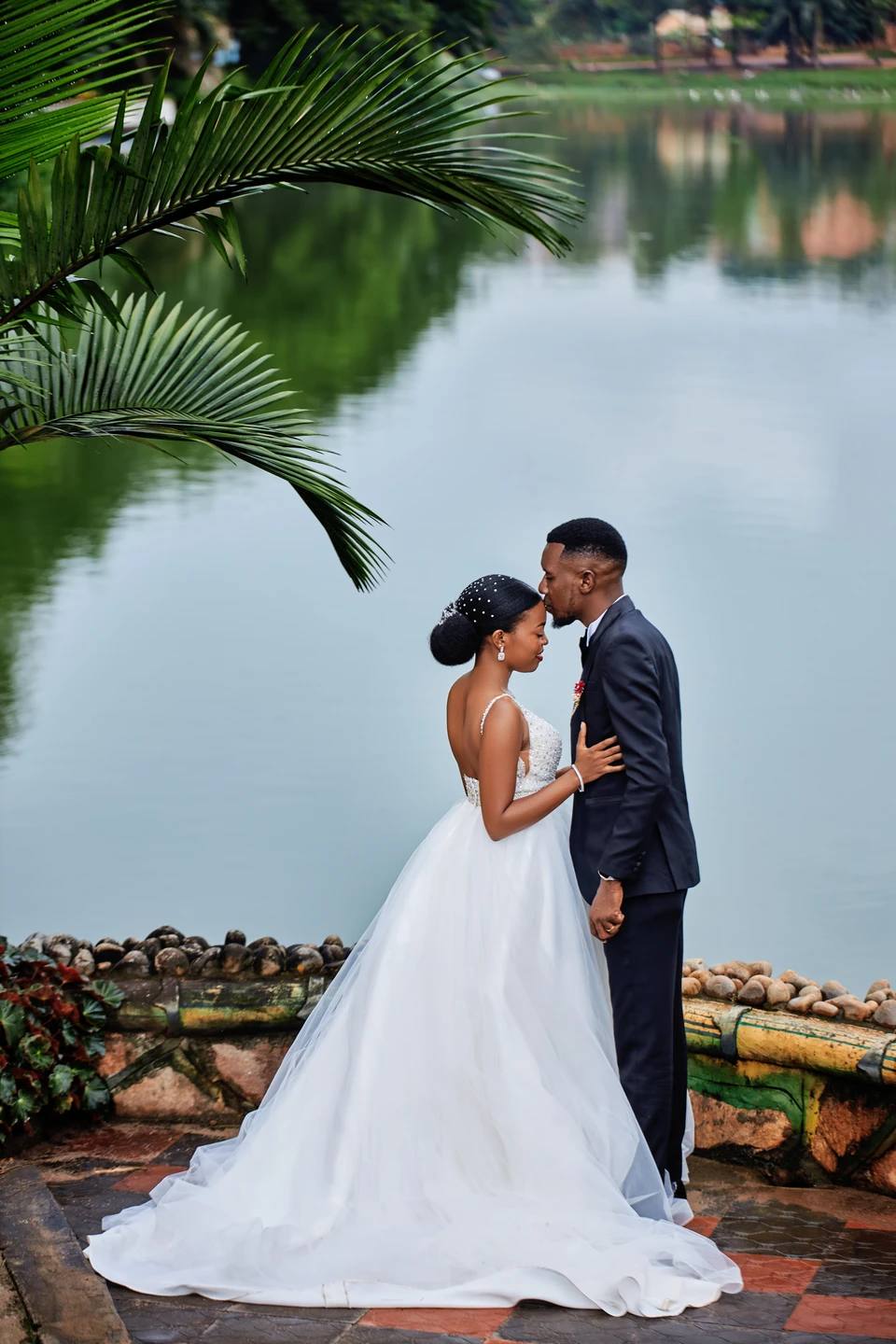 Bride and groom embracing beneath a palm tree